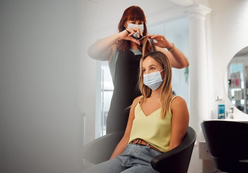 Covid, mask and hairdresser women in salon with protection for professional hair grooming business. Los Angeles hairstylist busy cutting with medical face barrier for virus transmission safety.