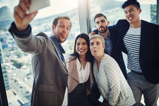 Letting all their expressions out. a group of businesspeople taking a selfie together in an office.