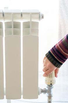 Radiator adjustment closeup. Female hand adjusting radiator temperature