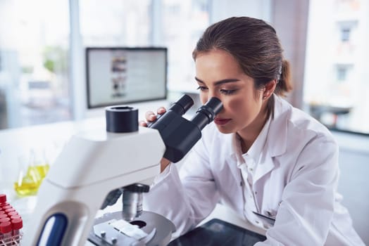 Research, scientist and woman with a microscope, laboratory and experiment for results, cure and healthcare. Female person, science and researcher with lab equipment, sample analysis and medicine