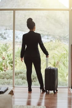 Travel, luggage and glass with a business black woman standing in a hotel looking at the view. Corporate, window and accommodation with a female employee in a luxury or modern apartment for work