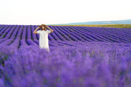 Young woman in a white dress walking in a lavender field, close up