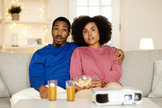 Black Couple Watching Horror Movie Using Home Cinema Projector Indoor