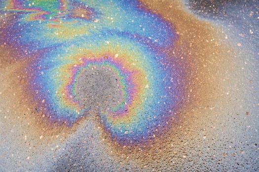 Texture plan of an iridescent oil or gasoline spill on wet pavement, top view.