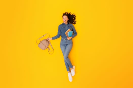 Top View Of Enthusiastic Student Woman Grasping Backpack, Yellow Backdrop