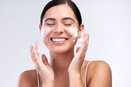 Skincare, foam wash and woman in a studio for natural, cosmetic and beauty hygiene routine. Wellness, health and female model cleaning her face with a facial cleanser isolated by a white background.