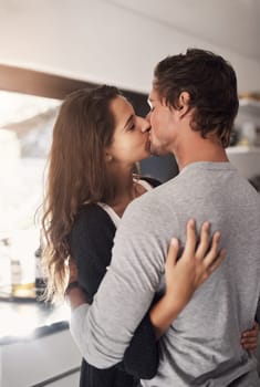 Young, couple and kissing in home for love, romantic bond and intimacy of special moment together. Man, woman and romance of partners with kiss for happy relationship, passionate affection and care.
