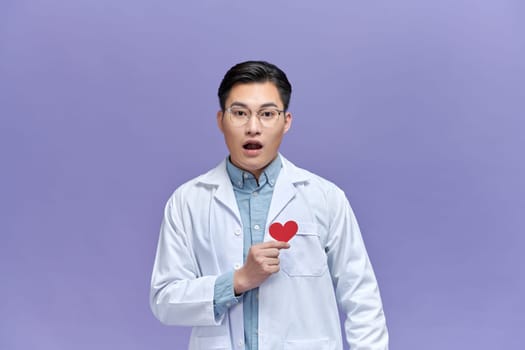 cardiologist doctor man holding red heart over purple background with angry face