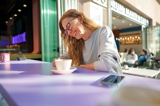 Young casual woman sitting at the table in coffeeshop