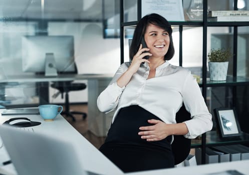 Multitasking is my super power. an attractive pregnant businesswoman sitting alone in the office and using her cellphone.