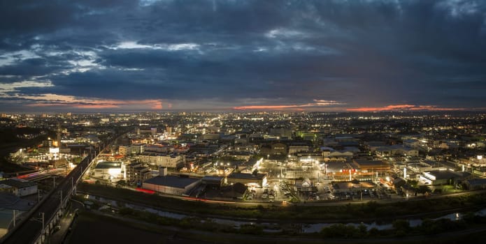 Panoramic aerial view of elevated train tracks and city lights after sunset