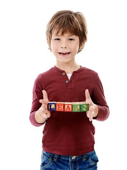 As you learn so you shall grow. Studio shot of a cute little boy holding building blocks that spell the world learn against a white background.