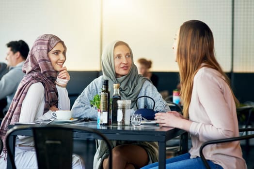 Friends, smile and Muslim women in cafe, bonding and talking together. Coffee shop, happy and Islamic girls, group or people chat, conversation and discussion for social gathering in restaurant.