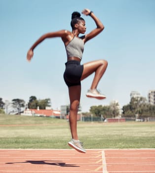 Fitness, jump or black woman runner on a race track in training, cardio workout or sports exercise in summer. Jumping, running and healthy African girl sprinter on a mission for goals in a stadium