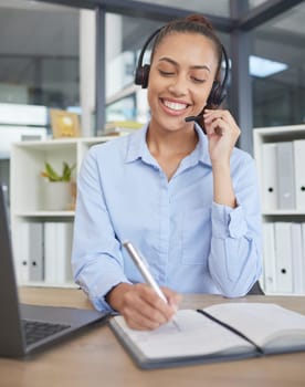Call center, woman and writing notes for customer service, telemarketing sales or consulting at office desk in agency. Happy receptionist, communication and planning in notebook, solution and telecom.