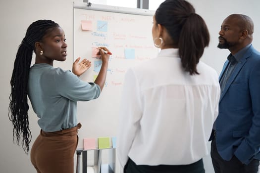 Black woman, business schedule and whiteboard writing for company planning with sticky notes. African female employee, startup meeting and collaboration of staff working with teamwork or conversation