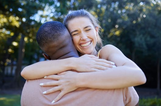 Love, interracial and couple hug, outdoor and smile for bonding, romance and loving together. Romantic, black man and woman embrace in nature, relationship and happiness in park, intimate and dating.