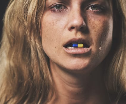 Depression, portrait and girl with pill in her mouth with emotional tears on face from crying. Sad, unhappy and isolated woman with mental health problem taking psychiatry medicine closeup.