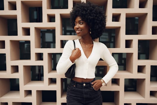 Stylish pretty african woman with Afro hairstyle posing near geometric wall