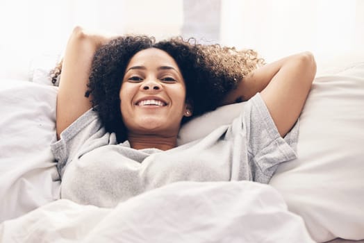 Black woman, wake up and portrait in home bedroom after sleeping or resting alone. Peace, bed relax and comfort of happy female awake after sleep on comfortable pillow and blankets for healthy rest.