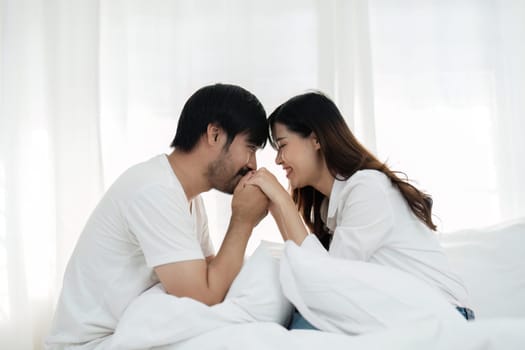 Young couple sitting in bed with pillows in modern bedroom