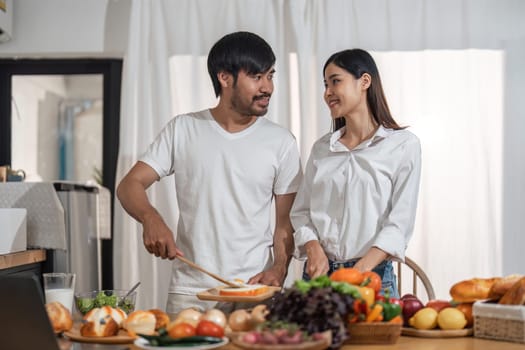 Happy smiling couple cooking together and healthy eating concept - couple cooking food at home kitchen