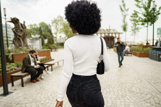 Back view of african woman walking in city