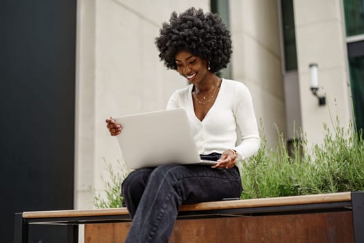 Young businesswoman working using laptop sitting on the bench in the city