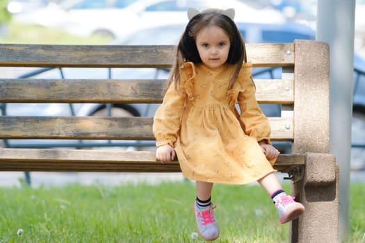 Portrait of a four-year-old girl sitting on a park bench.