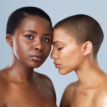 Our love is like no other. Portrait of two beautiful young women standing close to each other against a grey background.