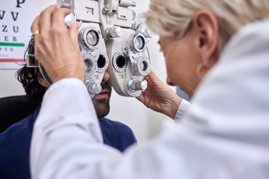Doctor with customer in vision test or eye exam for eyesight by doctor, optometrist or ophthalmologist. Senior optician helping check retina health of a man, patient or client with medical insurance