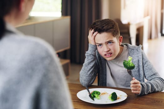 Disgust, food and child with vegetables in home for nutrition, health and cooking. Lunch, angry and dinner with boy and refuse to eat broccoli at tablet for eating problem, frustrated and dislike