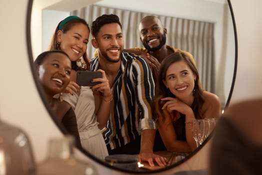 Group of friends, phone and mirror selfie for party, celebration or New Years together. Young people reflection, diversity or smartphone to connect, smile or social gathering to enjoy dinner or relax