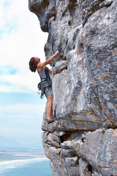 Rock climbing, blue sky and challenge with woman on mountain for adventure, travel and explore. Strong, freedom and cliff with female climber training in nature for courage, safety and workout.