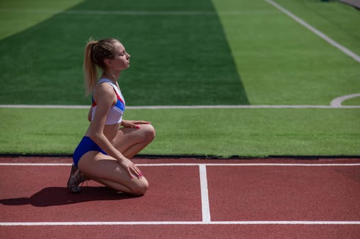 Young caucasian woman is ready to run in the stadium outdoors.