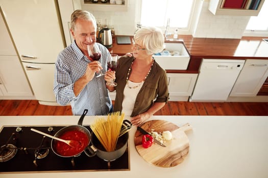 Top view, wine or old couple cooking food for a healthy vegan diet together with love in retirement at home. Happy senior woman drinking or bonding in house kitchen with mature husband at dinner