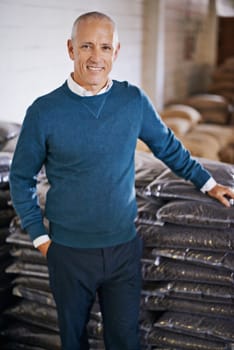We only import the finest beans. Portrait of a mature man standing by bags of coffee in a distribution warehouse.
