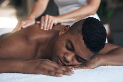 Comfortable and carefree. a young man getting a back massage at a spa.