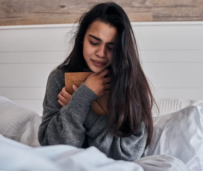 Sad, loss and woman crying with a photo for memory while in bed in the morning. Depression, tears and girl with a picture frame in the bedroom during grief, sadness and sorrow about death in a house