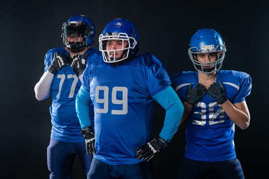 Portrait of three men in blue uniforms for American football on a black background.