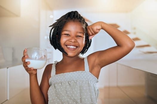 Milk, portrait and African girl with muscle from healthy drink for energy, growth and nutrition in the kitchen. Happy, smile and child flexing muscles from calcium in a glass and care for health