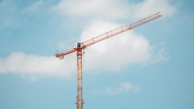 Tower crane in construction site over blue sky with clouds 