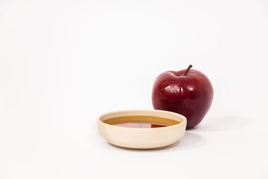 Red apple and bowl of honey isolated on a white background