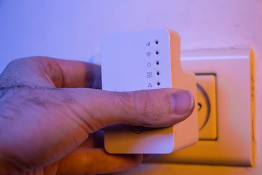 Man insert WiFi repeater into electrical socket on the wall