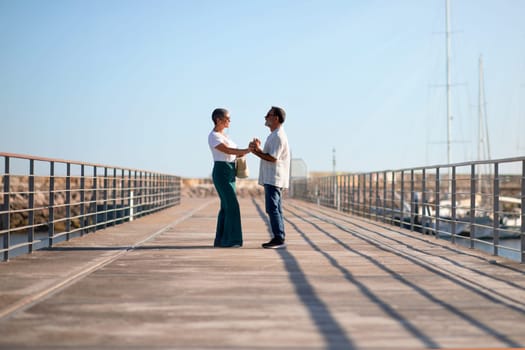 Loving Senior Couple Standing Holding Hands At Marina Pier Outside