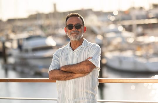 Mature Man Posing Crossing Hands Near Yachts At Marina Outside