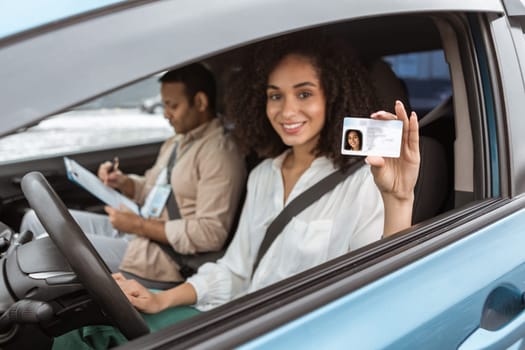 Cheerful Arabic Lady Showing Driving License Card Through Automobile Window