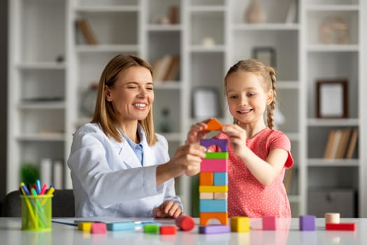 Learning Through Play. Little Girl And Child Development Specialist Playing Wooden Bricks