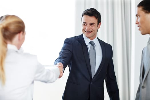 Im looking forward to working with you. A positive businessman shaking hands with a coworker during a meeting.