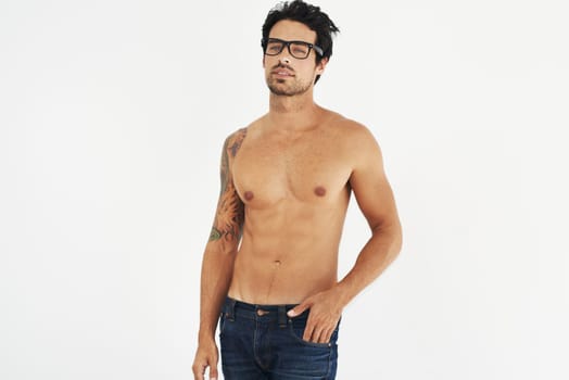 Portrait, shirtless and glasses with a sexy man model in studio on a white background for masculine desire. Body, tattoo and manly with a handsome young male nerd posing topless for rugged sensuality